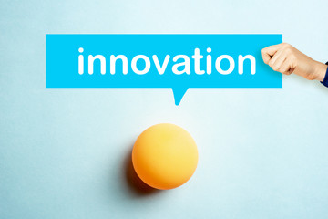 Concept of Innovation with a hand showing a speech bubble and yellow ping pong ball on blue background