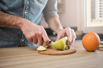 Close up look of male hands, how he preparing fruits for salad in the morning at home.