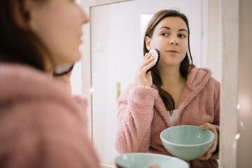 Mirrored image of woman cleansing her face