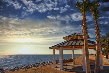 A seaside pavilion under palm trees on a sunny day