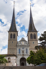 Exterior view of the St. Leodegar Church (Hofkirche), a Roman Catholic church in old town of Lucerne on a sunny summer day with blue sky cloud in background, Switzerland