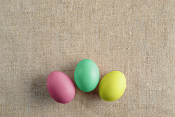 Top view of three bright painted easter eggs on canvas surface. Colorful easter eggs decoration. Flat lay, top view. with copy space for text.