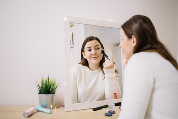 Happy woman makeup in front of a mirror