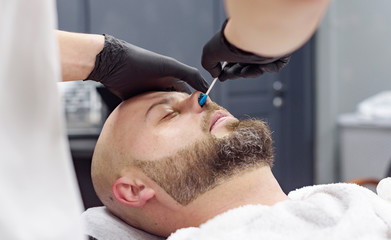 beard modeling in Barber shop, removing hair from the nose and ears with wax, male beauty and care concept