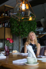 Blondie long hair woman is having lunch in a restaurant in the middle of the day.