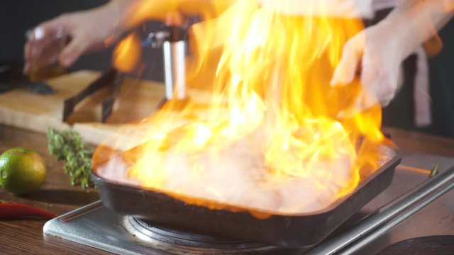 Chef making steak fillet mignon in flambe style on a grill pan. Oil and alcohol fire with open flames. Food on cuisine. Nutrition in gourmet kitchen. Making meal. Prepare food to eat. Delicious dish.