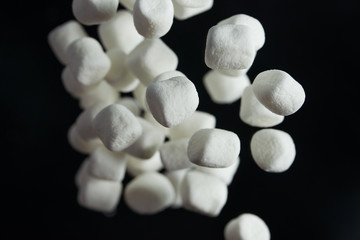 Falling marshmallows on a black background. Background of sweets for design, freezing in motion.