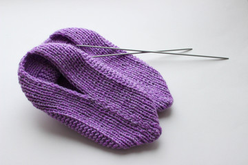 Handmade knitted pink slippers with knitting needles on white background