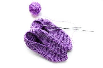 Handmade knitted pink slippers with knitting needles and ball of yarn. On white background you can easily place text or change the background