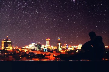 Man laying on a rooftop and admiring the night skyline