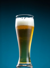 A tall glass filled with fresh foamy beer