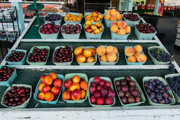 Close up of neatly arranged green cardboard boxes of colorful and shiny mixed fruit.Local food market ambient in the background. Variety of choice.