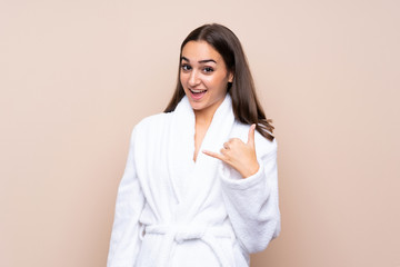 Young girl in a bathrobe over isolated background making phone gesture