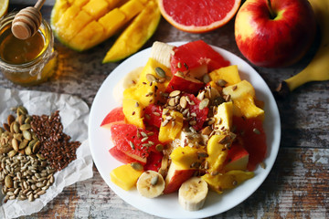 Selective focus. Fruit salad with honey and seeds on a white plate. Keto diet. Healthy food.
