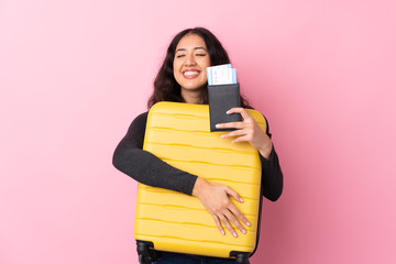 Mixed race woman over isolated pink background in vacation with suitcase and passport