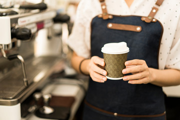 Fototapeta na wymiar Startup small business (SME) Asian women Smiling Barista waitress holding a white-hot coffee cup of latte with rosetta in a cafe coffee shop serving a client, business owner food and drink concept.
