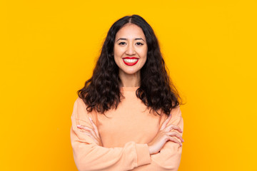 Spanish Chinese woman over isolated yellow background keeping the arms crossed in frontal position