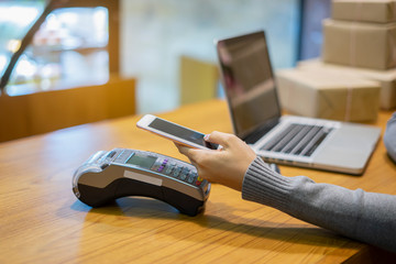 Asian girl holds QR Code on smartphone over credit card machine in supermarket shopping mall counter service for smart life security, internet of things,smart pay online for business service concept