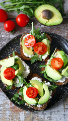 Healthy food. Avocado toasts with arugula and cherry tomatoes. Diet concept.