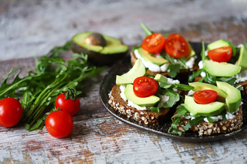 Healthy food. Avocado toasts with arugula and cherry tomatoes. Diet concept.