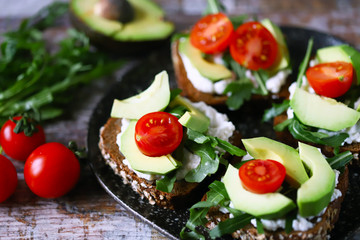Healthy food. Avocado toasts with arugula and cherry tomatoes. Diet concept.