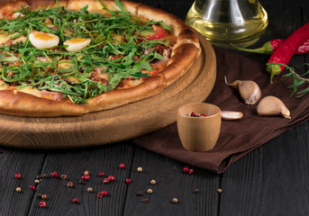 Pizza with chicken, arugula, cheese and onions on wooden rustic table.