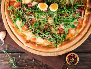 pizza with chicken and arugula on a brown wooden background
