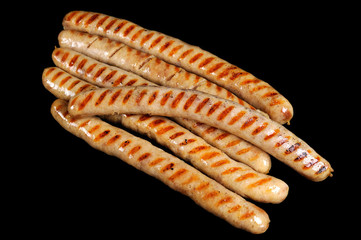Grilled sausages isolated on black background. Delicious barbecue fast food.
