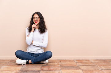 Fototapeta na wymiar Young woman sitting on the floor with glasses and smiling