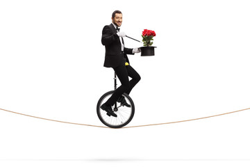 Magician performing a trick with red roses and riding a unicycle on a rope © Ljupco Smokovski