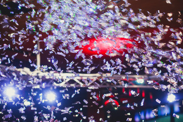Colourful confetti explosion fired on dance floor air during a concert festival, crowded concert hall with scene stage lights, rock show performance, with people silhouette