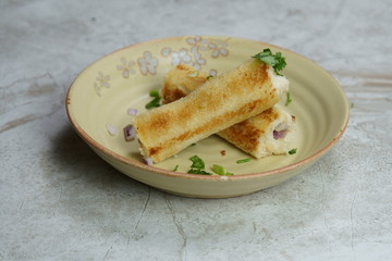 A stack of  toasted bread filled with a mixture of cheese, onion, peppers and cilantro on a plate.