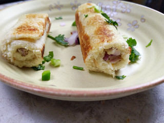 A stack of  toasted bread filled with a mixture of cheese, onion, peppers and cilantro on a plate.