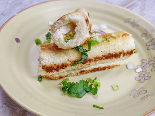 A stack of  toasted bread filled with a mixture of cheese, onion, peppers and cilantro on a plate.