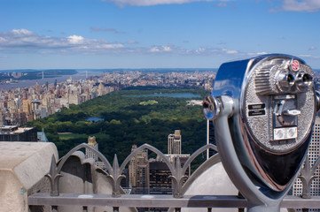 panoramic view of the skyline from  New York City with view over the Manhattan Central Park on a sunny day, in front a blurred zoom binoculars on Rockefeller Center