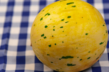 Whole melon fruits on a table on a blue and white tablecloth
