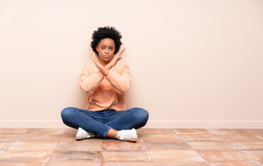 African american woman sitting on the floor making NO gesture