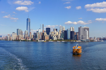 view across the water to the skyline of new york, yellow boat in front
