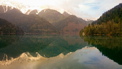 stones and trees overgrown with moss on the banks of a mountain river and a lake on the background of rocks