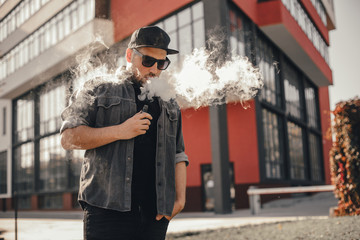 Young handsome man smoke with vape in urban location