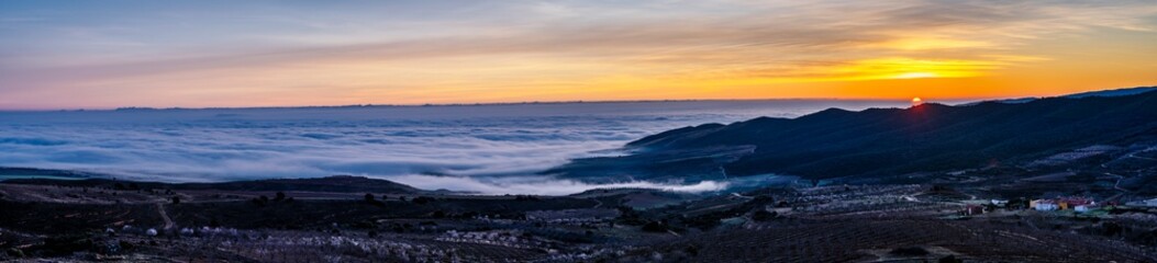 Fototapeta premium panoramic view of sunrise over the clouds on the mountain.