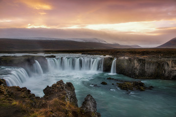 Beautiful long exposure shot at Godafoss waterfall in Iceland with warm light of sunset and smooth movement of water. Iceland is one of the famous place for landscape photography