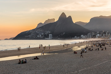 People relaxing and having fun on Ipanema beach at sunset with the Dois Irmãos (Two Brothers)...