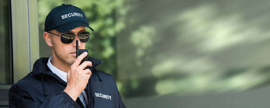Young Security Guard Talking On Walkie-talkie