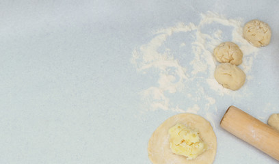 The process of making pies with filling. Dough with potato, flour and rolling pin on grey background. Russian food concept. Flat lay with copy space.