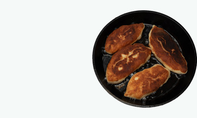 Delicious patties with filling during frying in oil in a pan on white background. Russian food concept. Flat lay with copy space.