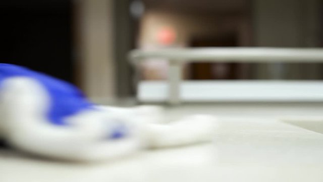4k Janitor cleaning medical office counter top using sanitizing antibacterial spray in hospital doing custodian work alone at night with latex gloves on and working hard	