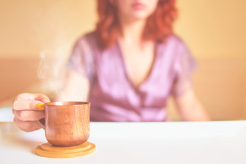 Amazing woman in a purple silk robe drinking coffee early in the morning in bed. Wooden cup of latte on the white tray. Breakfast concept