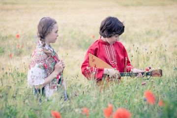 Portrait of a boy and a girl in the field. The girl’s shoulders are covered with a shawl with...