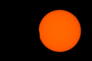 The start of a partial solar eclipse. Sunspots are present, and turbulence can be seen on the surface of the sun, especially around the edge (this is not noise).